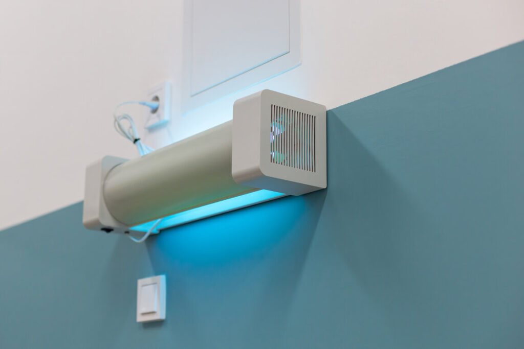 Wall mounted UV sterilization lamp emitting blue light for disinfection in a hospital setting